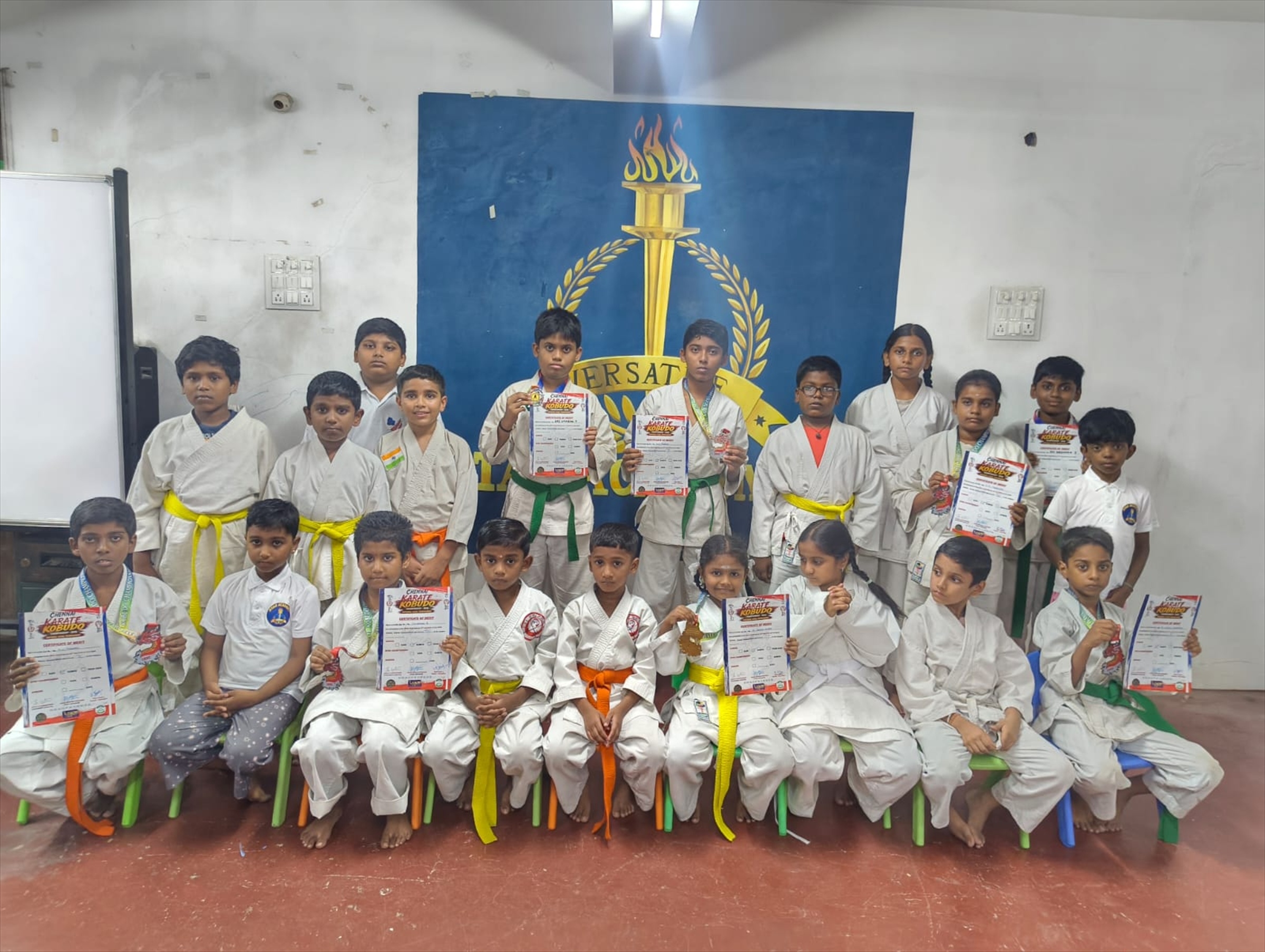 Karate students wearing coloured belts and holding certificates after the August 2026 belt grading